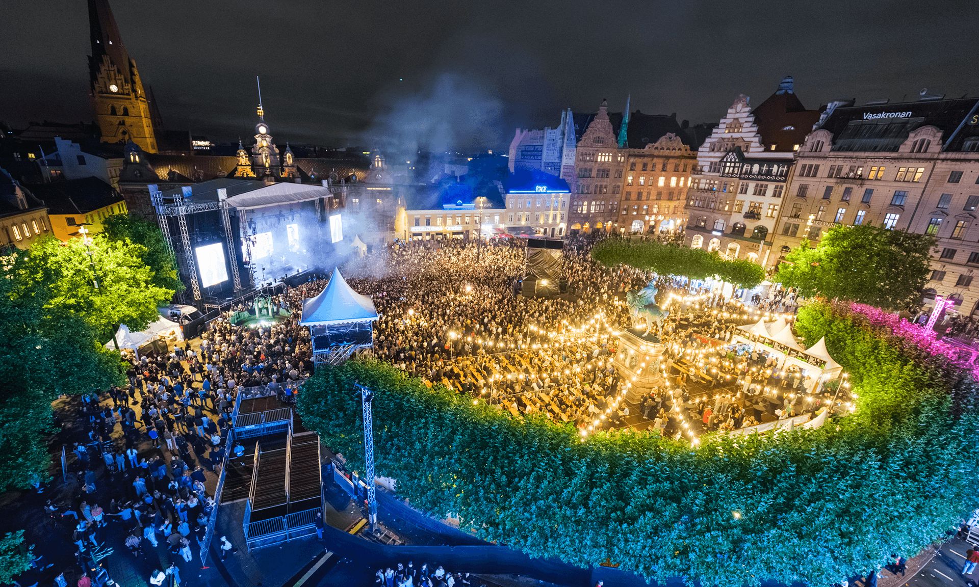 Bild på Stortorget i Malmö under Malmöfestivalen på kvällen, där det är fullt av publik och en stor scen.