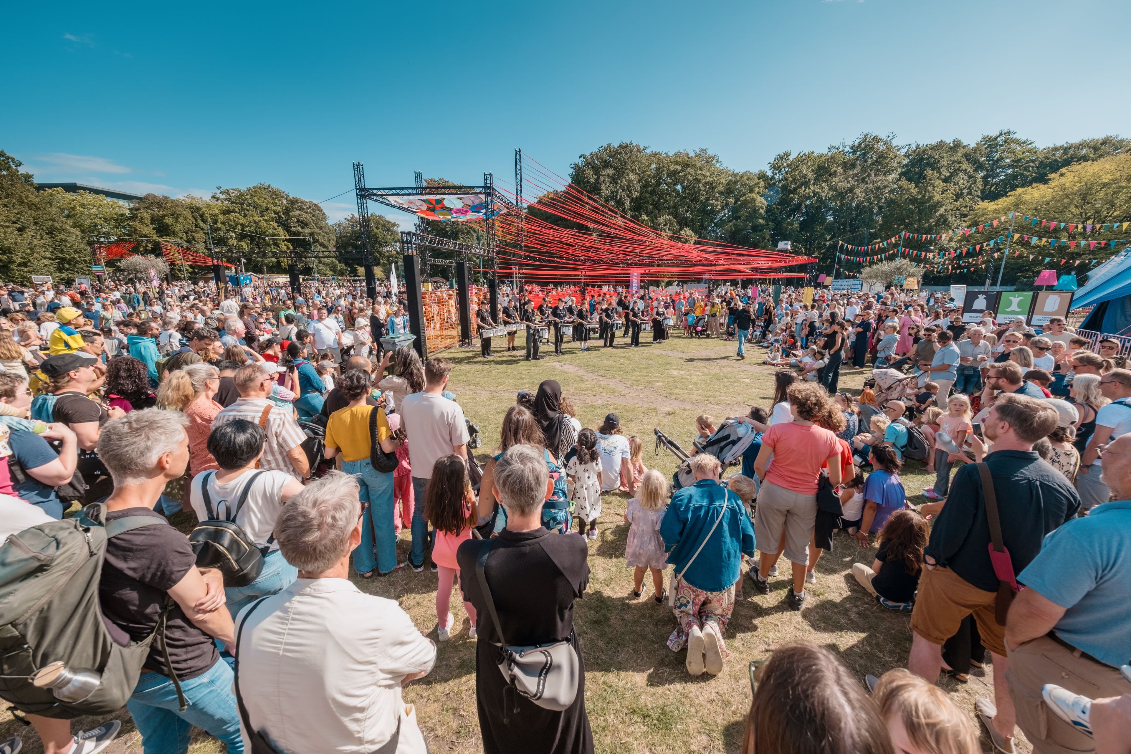 Stor publik samlad runt en utomhusscen i en park under ett uppträdande på Malmöfestivalen.