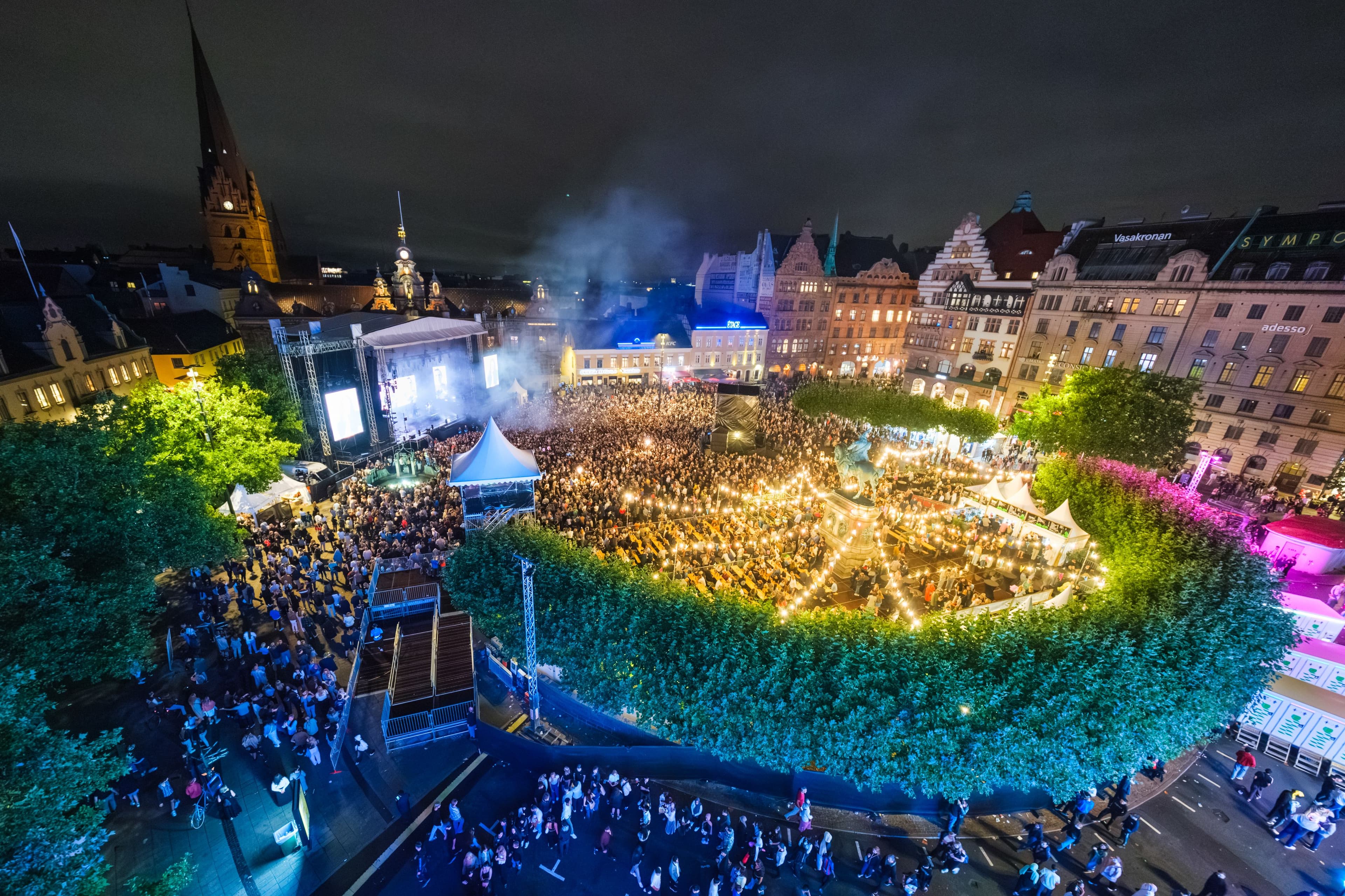 Luftfoto på kväll över Stortorget i Malmö med scen, publik och upplyst uteservering under Malmöfestivalen.