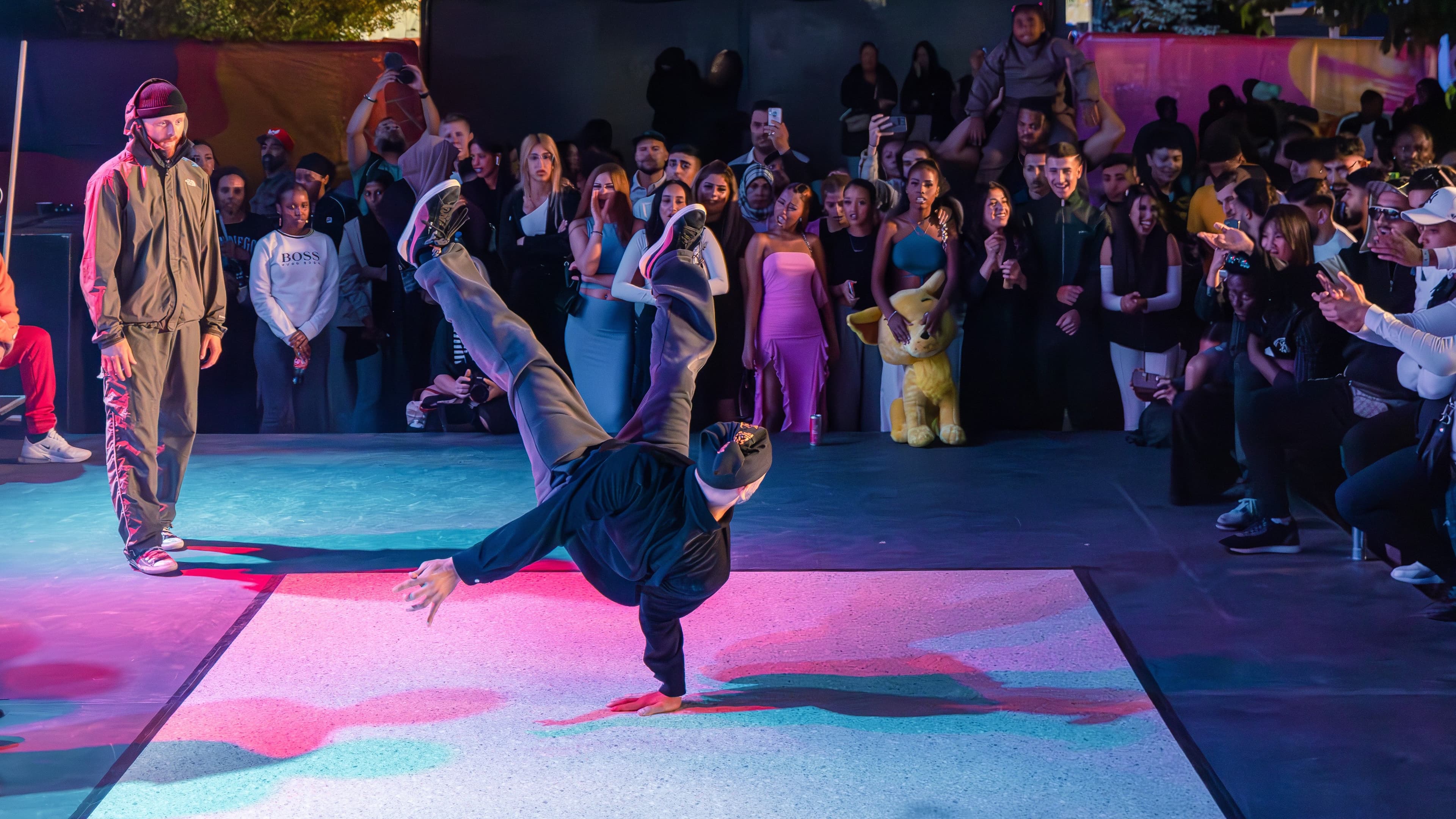 Publik tittar på två manligare dansare. En av dem är i rörelse, den andra står still.